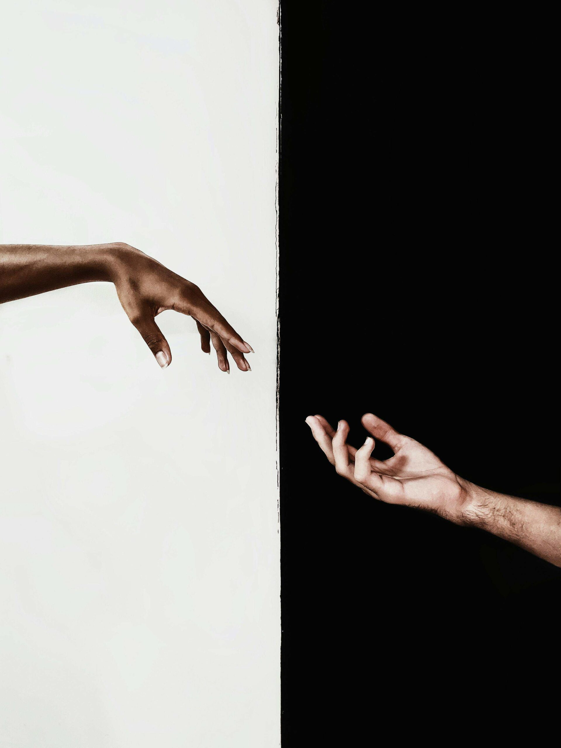 Deux mains se tendant l’une vers l’autre entre fond blanc et fond noir, symbole de la dualité