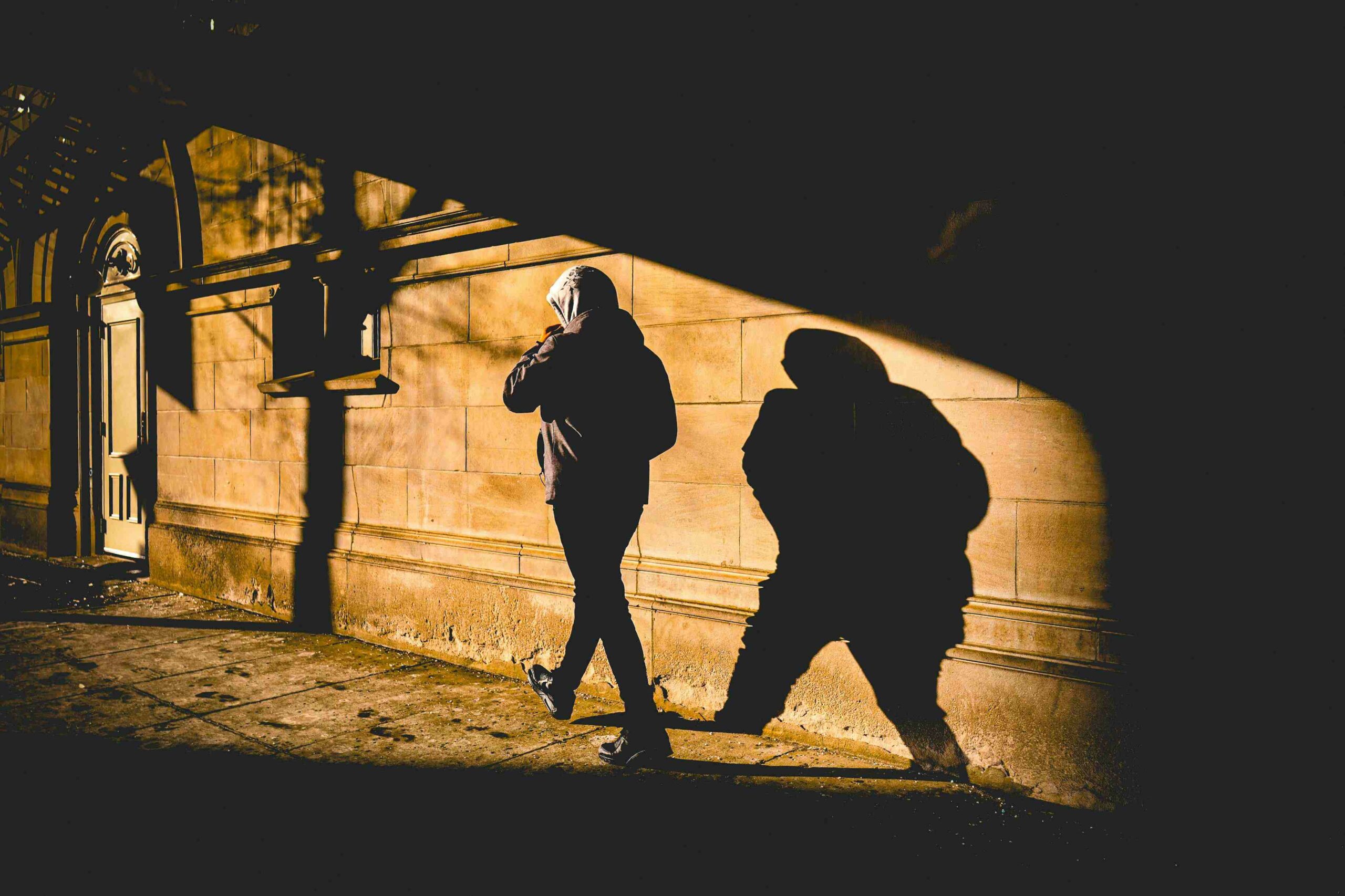 Silhouette d’une personne marchant dans la lumière avec son ombre projetée sur un mur